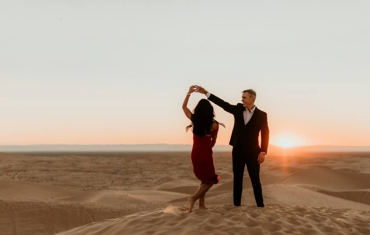 A couple dancing together at sunset on a desert sand dune