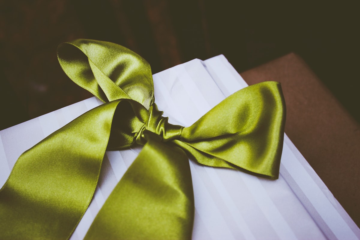 A gift box wrapped with a green ribbon, representing a client gift phone case ready to give