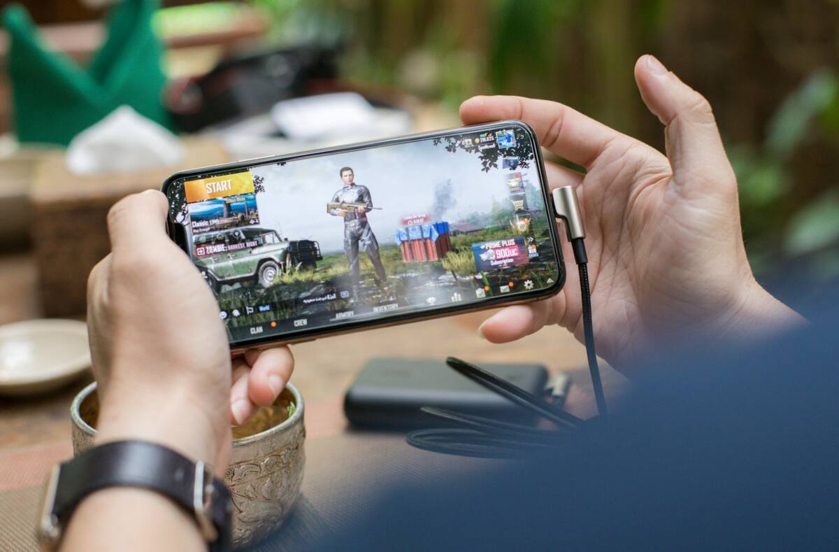 Hands holding a phone in a gamer phone case during a mobile gaming session