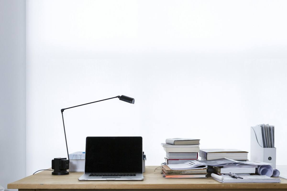 Organized desk with laptop, books, and stacked papers