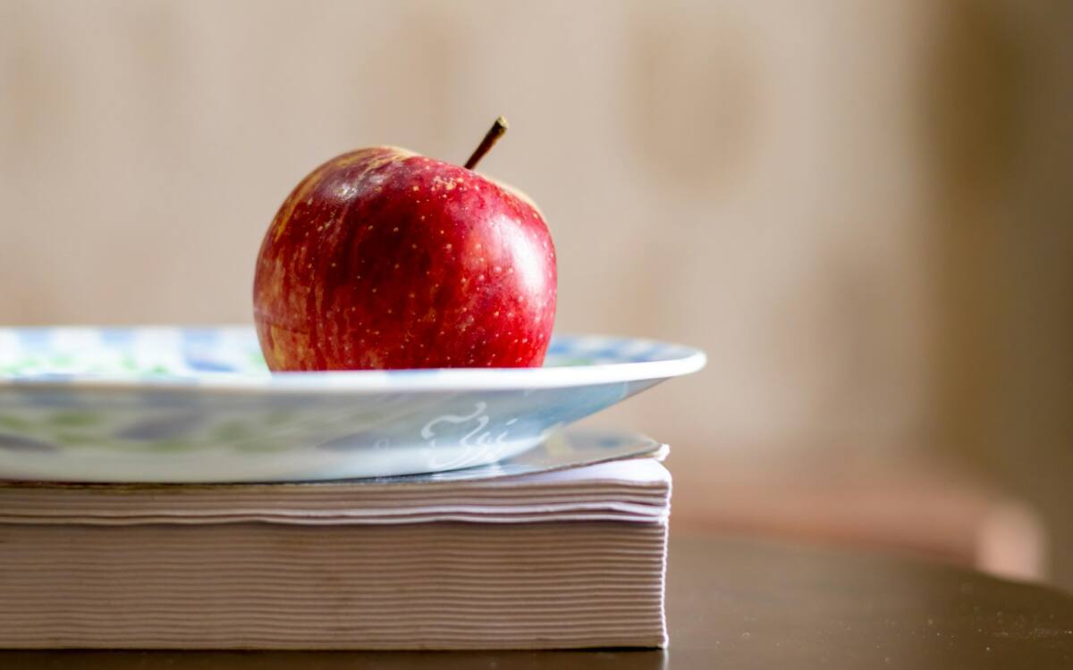 A teacher appreciation phone case gift styled with an apple and books