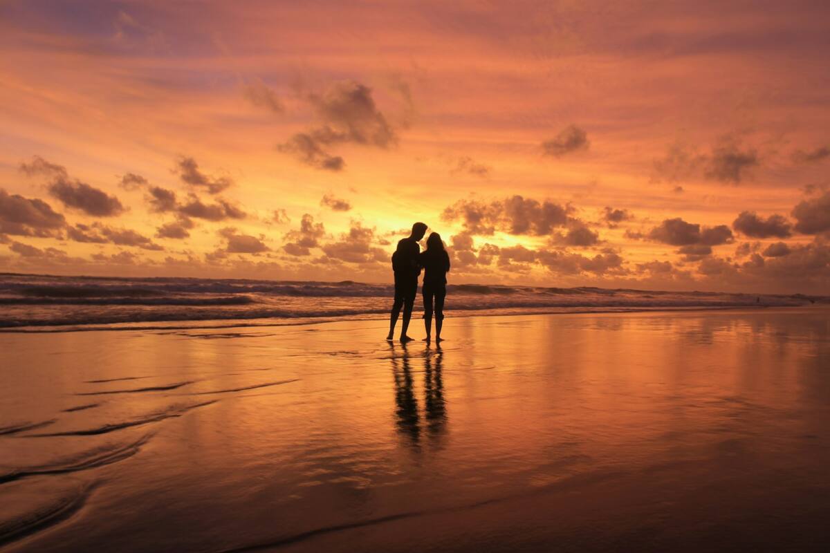 A couple silhouette embracing on the beach at sunset, representing a matching couple phone case set
